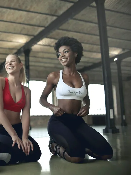 Three women laughing on mats after a class