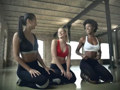 Three women laughing on mats after a class