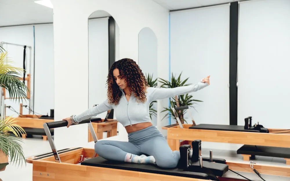 Instructor seated on a reformer with her arms open