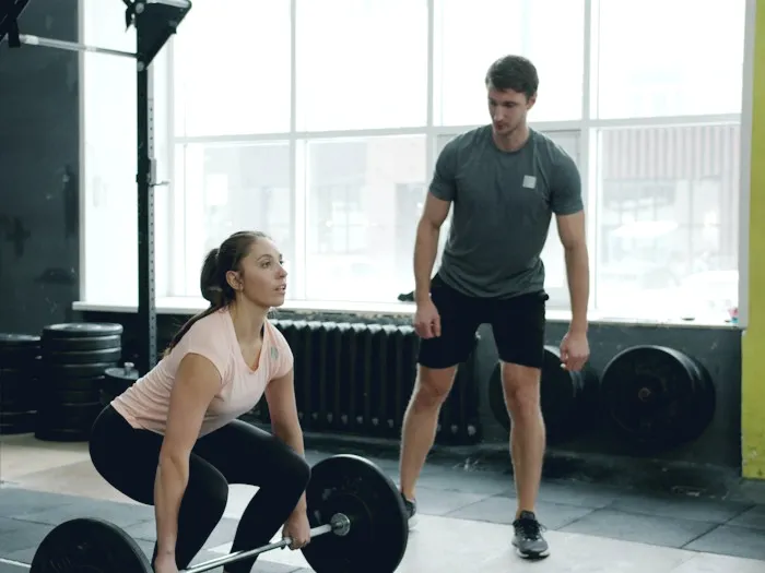 Personal trainer coaching a client with a barbell