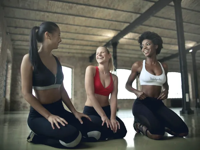 Three women laughing on mats after a class
